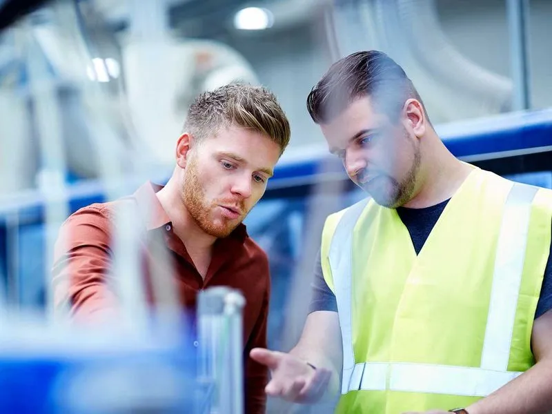 Zwei Männer betrachten und diskutieren gemeinsam einen technischen Plan.